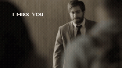 A Man In A Suit And Tie Is Standing In Front Of A Wall With The Words I Miss You Above Him GIF