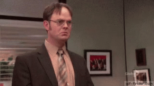 A Man In A Suit And Tie Is Standing In Front Of A Window In An Office With His Arms Outstretched . GIF