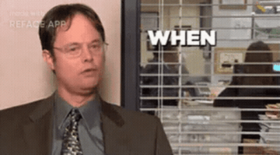 A Man In A Suit And Tie Is Standing In Front Of A Window With Blinds And Says `` When '' . GIF