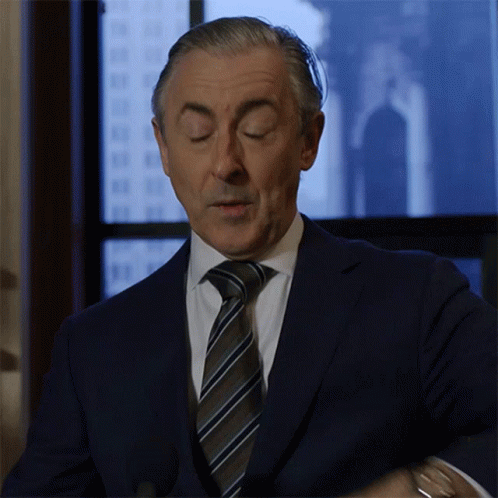 A Man In A Suit And Tie Is Standing In Front Of A Window With His Eyes Closed GIF