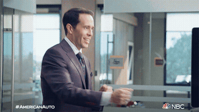 A Man In A Suit And Tie Is Standing In Front Of A Window With The Nbc Logo On The Bottom GIF