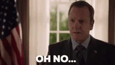 A Man In A Suit And Tie Is Standing In Front Of An American Flag And Saying `` Oh No '' . GIF