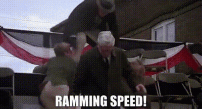A Man In A Suit And Tie Is Standing In Front Of An American Flag With The Words Ramming Speed Written On It . GIF