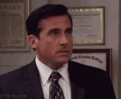A Man In A Suit And Tie Is Standing In Front Of Framed Awards . GIF