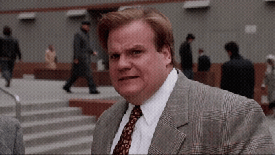 A Man In A Suit And Tie Is Standing In Front Of Stairs GIF