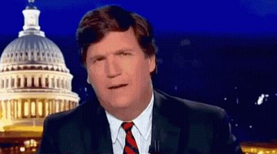 A Man In A Suit And Tie Is Standing In Front Of The Capitol Building At Night . GIF
