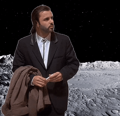 A Man In A Suit And Tie Is Standing In Front Of The Moon GIF