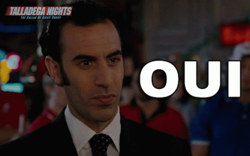 A Man In A Suit And Tie Is Standing In Front Of The Word Oui GIF