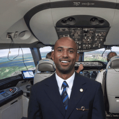 A Man In A Suit And Tie Is Standing In The Cockpit Of A 787 Dreamliner GIF