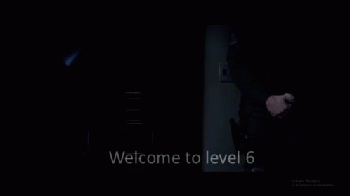 A Man In A Suit And Tie Is Standing In The Dark With The Words Welcome To Level 6 Below Him GIF
