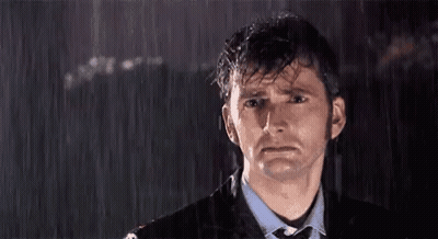 A Man In A Suit And Tie Is Standing In The Rain Looking Sad GIF