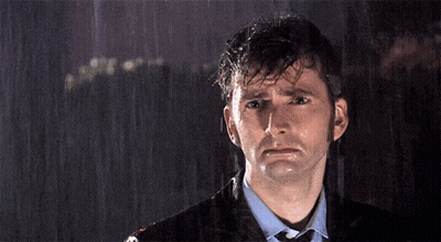 A Man In A Suit And Tie Is Standing In The Rain With His Eyes Closed GIF