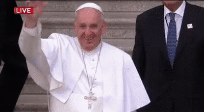 A Man In A Suit And Tie Is Standing Next To A Man In A White Robe Who Is Waving . GIF