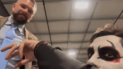 A Man In A Suit And Tie Is Standing Next To A Man With Clown Makeup On His Face GIF