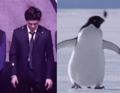 A Man In A Suit And Tie Is Standing Next To A Penguin On The Snow . GIF