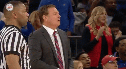 A Man In A Suit And Tie Is Standing Next To A Referee GIF