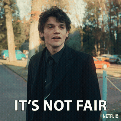 A Man In A Suit And Tie Is Standing Next To A Sign That Says " It 'S Not Fair " GIF
