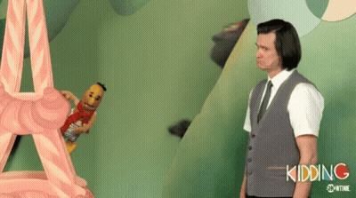 A Man In A Suit And Tie Is Standing Next To A Stuffed Animal That Says Kidding On It . GIF