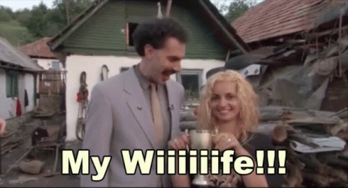 A Man In A Suit And Tie Is Standing Next To A Woman Holding A Trophy And Says My Wiilife !!! GIF