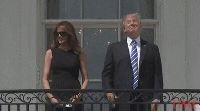 A Man In A Suit And Tie Is Standing Next To A Woman In A Black Dress . GIF