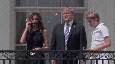A Man In A Suit And Tie Is Standing Next To A Woman In A Black Dress And A Boy . GIF
