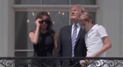 A Man In A Suit And Tie Is Standing Next To A Woman In A Black Dress And A Man In A White Shirt . GIF