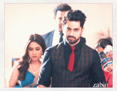 A Man In A Suit And Tie Is Standing Next To A Woman In A Dress GIF