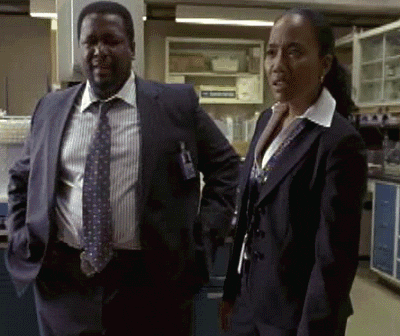 A Man In A Suit And Tie Is Standing Next To A Woman In A Suit GIF