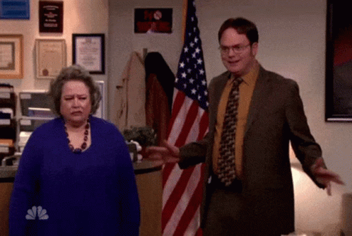 A Man In A Suit And Tie Is Standing Next To A Woman In Front Of An American Flag . GIF