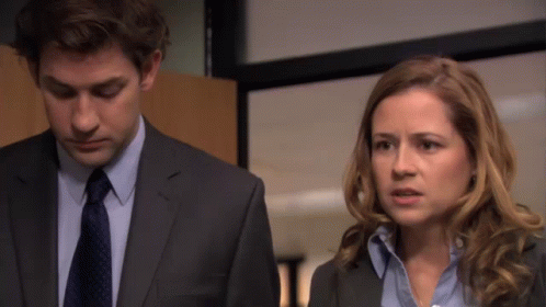 A Man In A Suit And Tie Is Standing Next To A Woman GIF