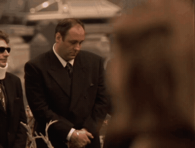 A Man In A Suit And Tie Is Standing Next To A Woman GIF