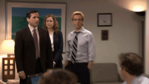 A Man In A Suit And Tie Is Standing Next To A Woman GIF