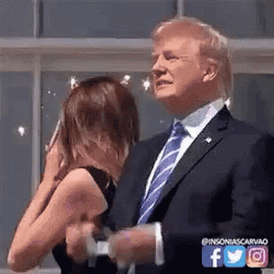 A Man In A Suit And Tie Is Standing Next To A Woman Who Is Covering Her Face . GIF