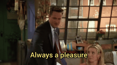 A Man In A Suit And Tie Is Standing Next To A Woman Who Is Sitting On A Couch . GIF