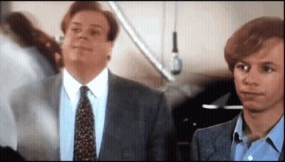 A Man In A Suit And Tie Is Standing Next To Another Man In A Blue Shirt GIF
