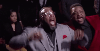 A Man In A Suit And Tie Is Standing Next To Another Man In A Red Suit . GIF