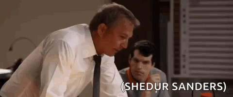 A Man In A Suit And Tie Is Standing Next To Another Man In A Room . GIF