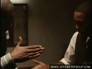 A Man In A Suit And Tie Is Standing Next To Another Man In A Room . GIF