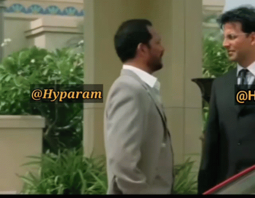 A Man In A Suit And Tie Is Standing Next To Another Man In A Suit And Tie With A Sign That Says @Hyparam GIF