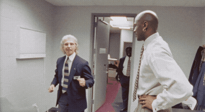 A Man In A Suit And Tie Is Standing Next To Another Man In A White Shirt And Tie GIF