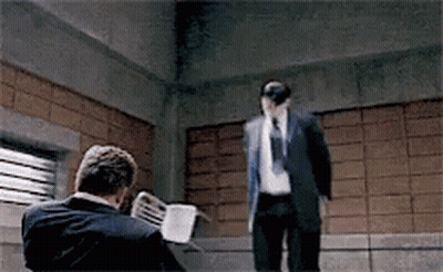 A Man In A Suit And Tie Is Standing Next To Another Man . GIF