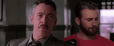 A Man In A Suit And Tie Is Standing Next To Another Man With A Beard . GIF