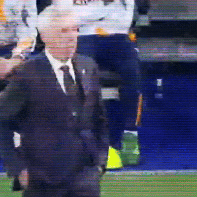 A Man In A Suit And Tie Is Standing On A Field GIF