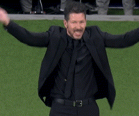A Man In A Suit And Tie Is Standing On A Field With His Arms Outstretched . GIF
