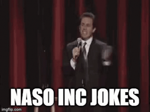 A Man In A Suit And Tie Is Standing On A Stage Holding A Microphone And Saying Naso Inc Jokes . GIF