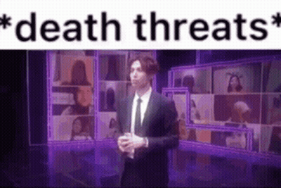 A Man In A Suit And Tie Is Standing On A Stage In Front Of A Purple Screen . GIF