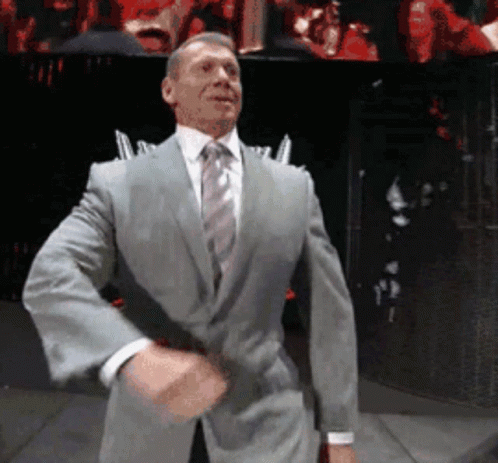 A Man In A Suit And Tie Is Standing On A Stage GIF