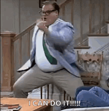 A Man In A Suit And Tie Is Standing On A Staircase . GIF