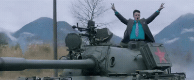 A Man In A Suit And Tie Is Standing On Top Of A Tank With His Arms In The Air GIF