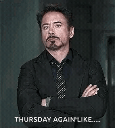 A Man In A Suit And Tie Is Standing With His Arms Crossed And A Beard . GIF